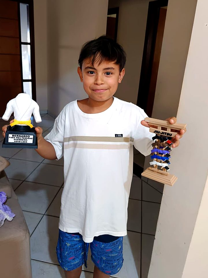 Menino segurando o troféu com faixa amarela e o porta-faixa