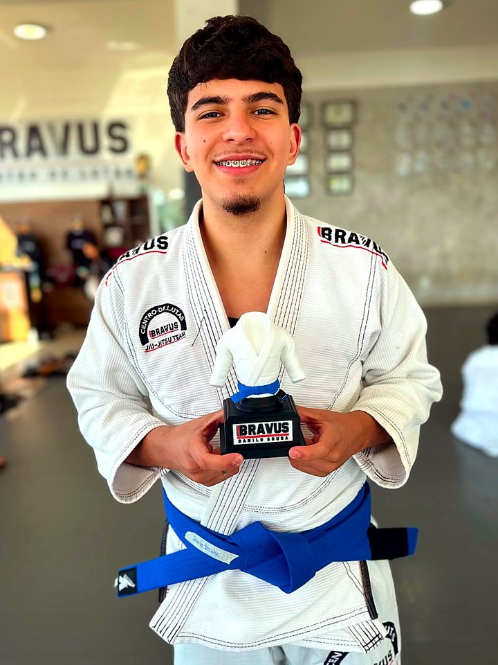 Aluno faixa azul na academia com o troféu personalizado