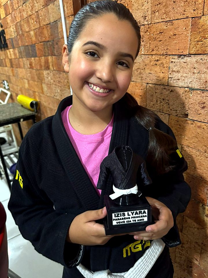 Menina sorrindo com o troféu que ganhou da avó