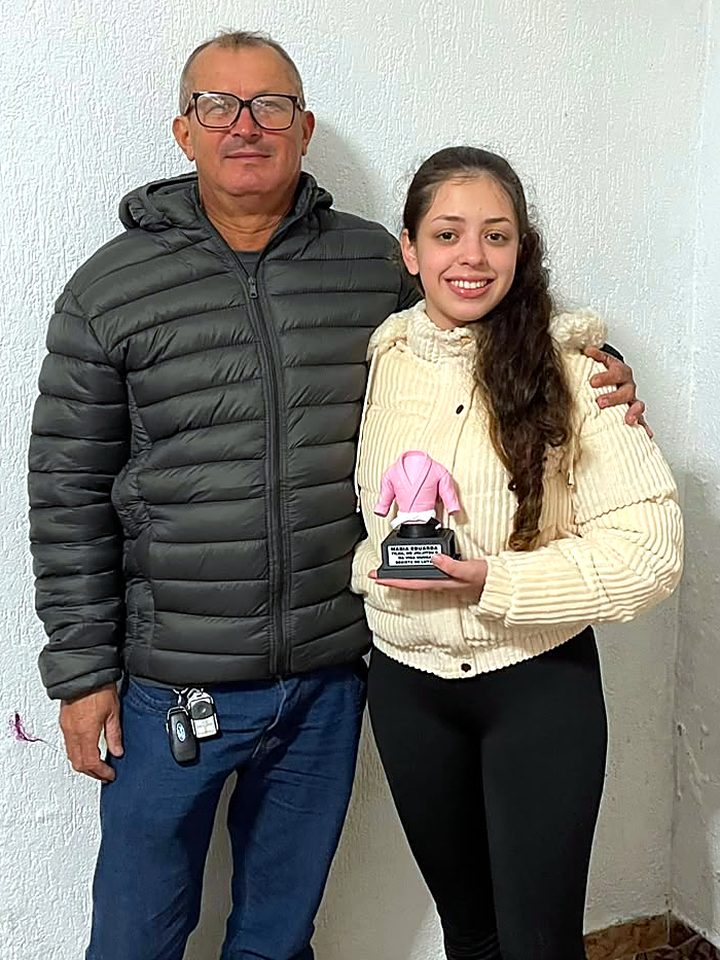 Pai abraçado com a filha, que segura o troféu de kimono rosa